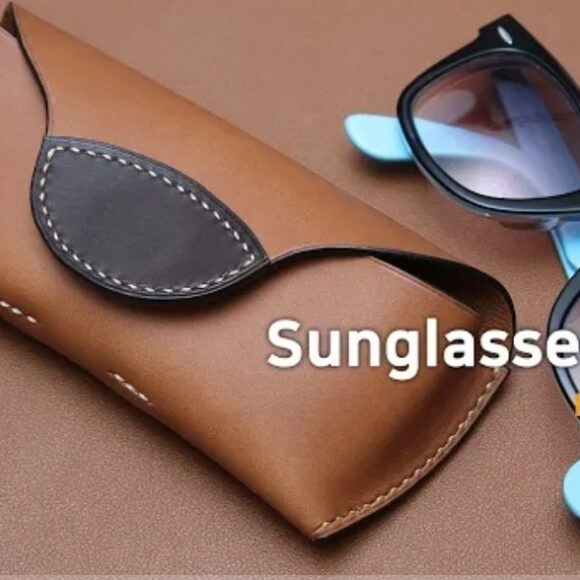 Футляр для солнцезащитных очков ручной работы из коричневой кожи с парой синих и черных солнцезащитных очков, лежащих рядом на коричневой поверхности, на заднем плане надпись "Футляр для солнцезащитных очков №40 PDF".