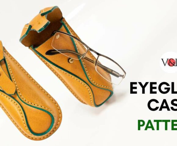 Сумка из коричневой кожи ручной работы с зеленой окантовкой, частично открытая, чтобы показать металлический инструмент внутри, на белой поверхности.