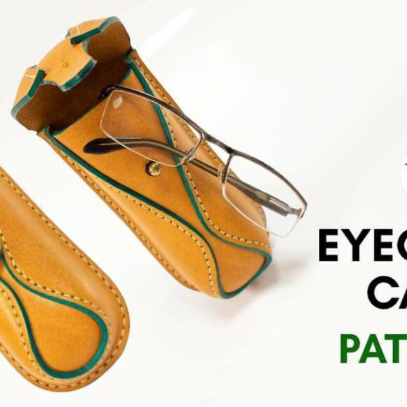 Сумка из коричневой кожи ручной работы с зеленой окантовкой, частично открытая, чтобы показать металлический инструмент внутри, на белой поверхности.